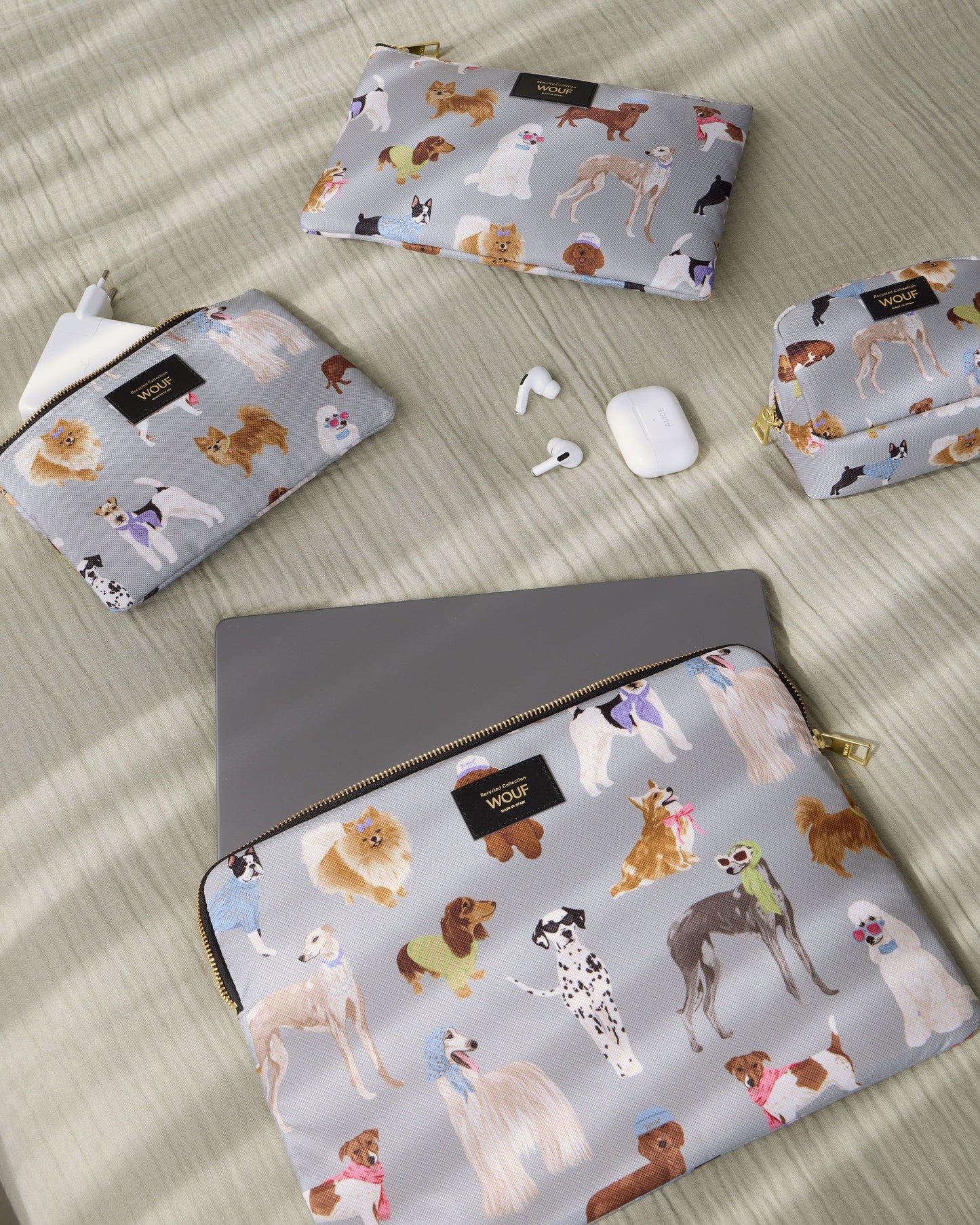 Lifestyle image of the Puppy 13-14 laptop sleeve with multicolour dog print on a grey background - Wouf