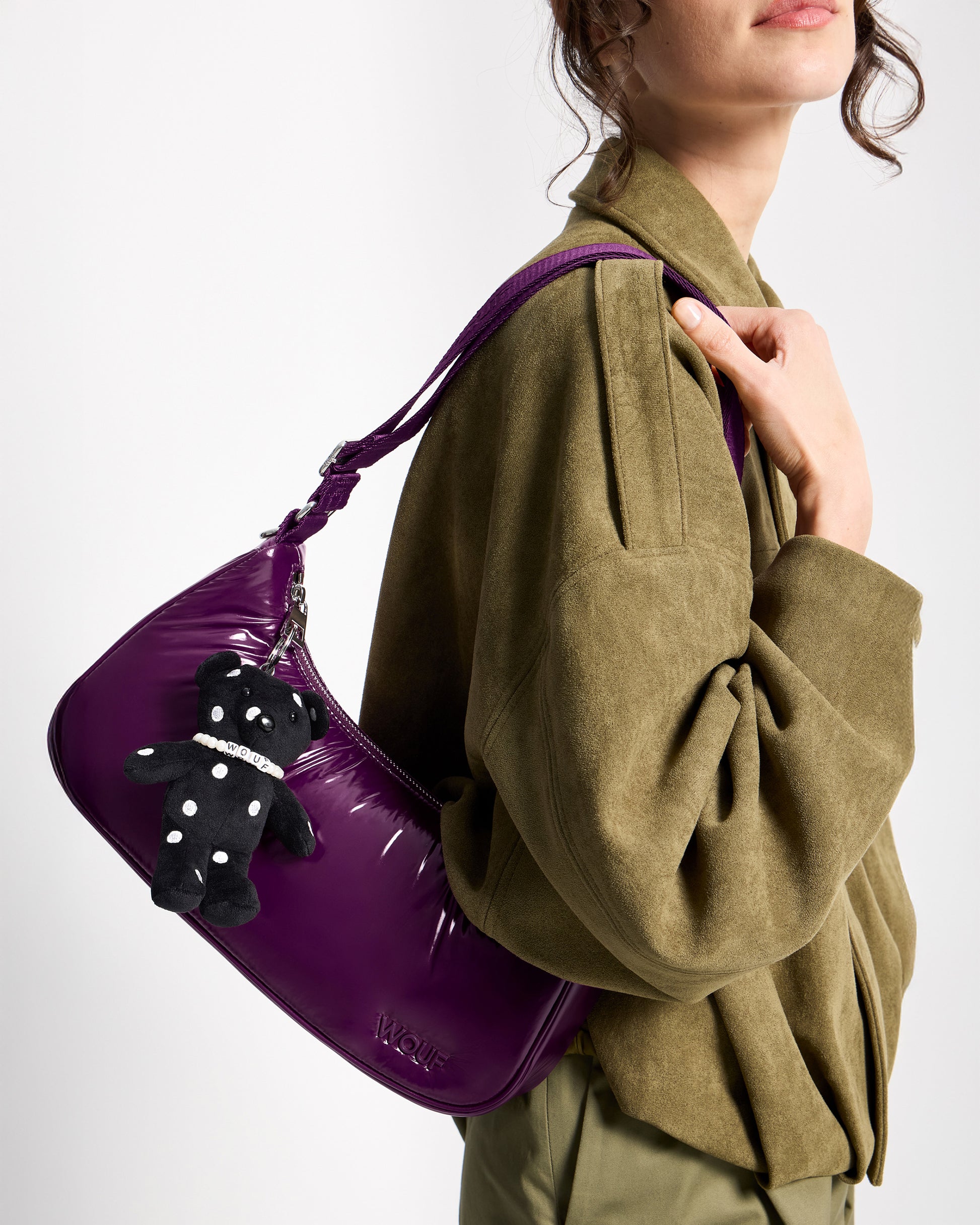 Detail of model with bear-shaped bag charm with embroidered white polka dots on a black background - Wouf