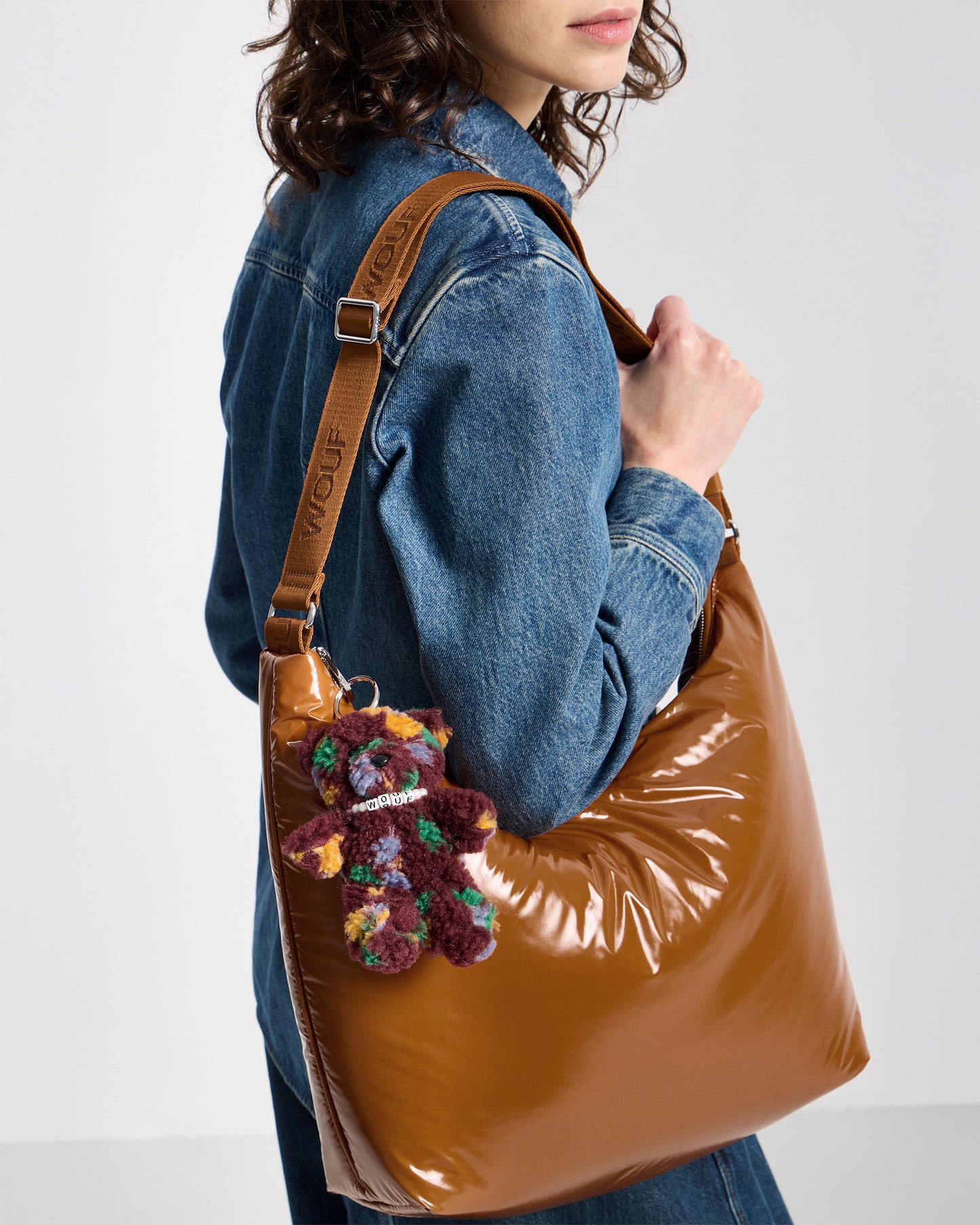 Detail of model with bear-shaped bag charm in teddy fabric with multicolour floral print on a burgundy background - Wouf