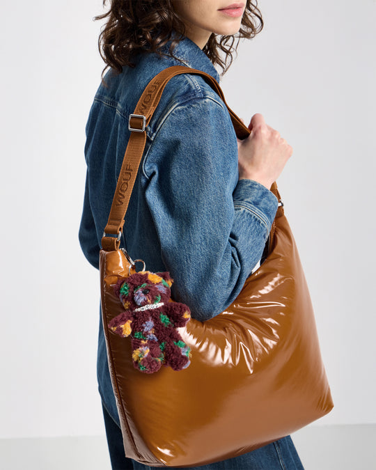 Detail of model with bear-shaped bag charm in teddy fabric with multicolour floral print on a burgundy background - Wouf