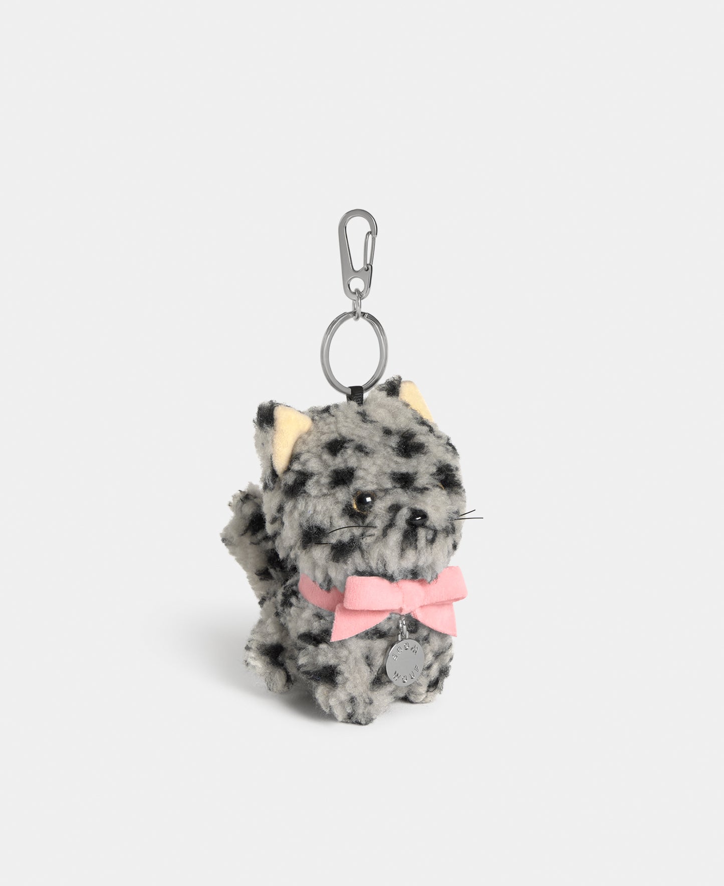Side view of the cat-shaped bag charm in grey teddy fabric with black animal print and a pink bow - Wouf