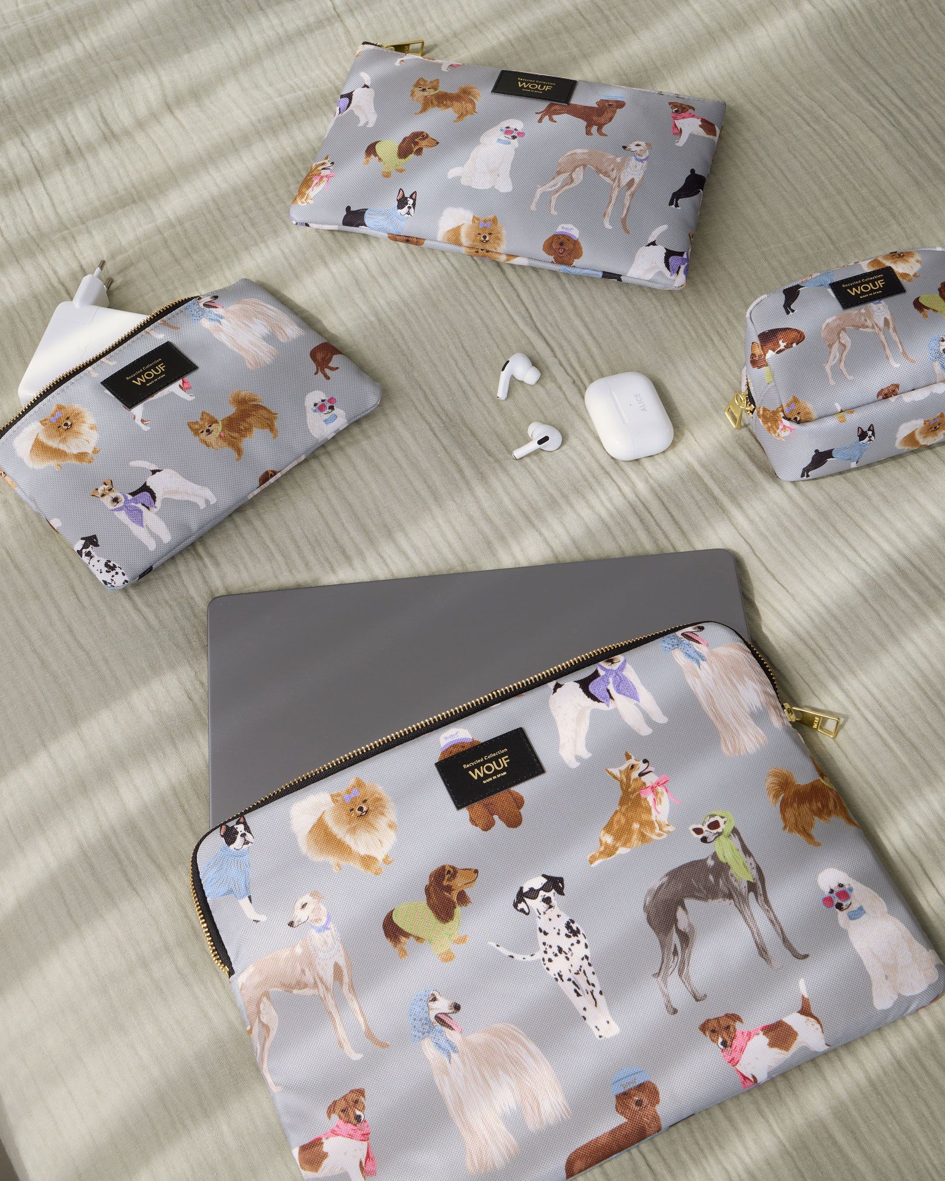 Lifestyle image of the Puppy 13-14 laptop sleeve with multicolour dog print on a grey background - Wouf
