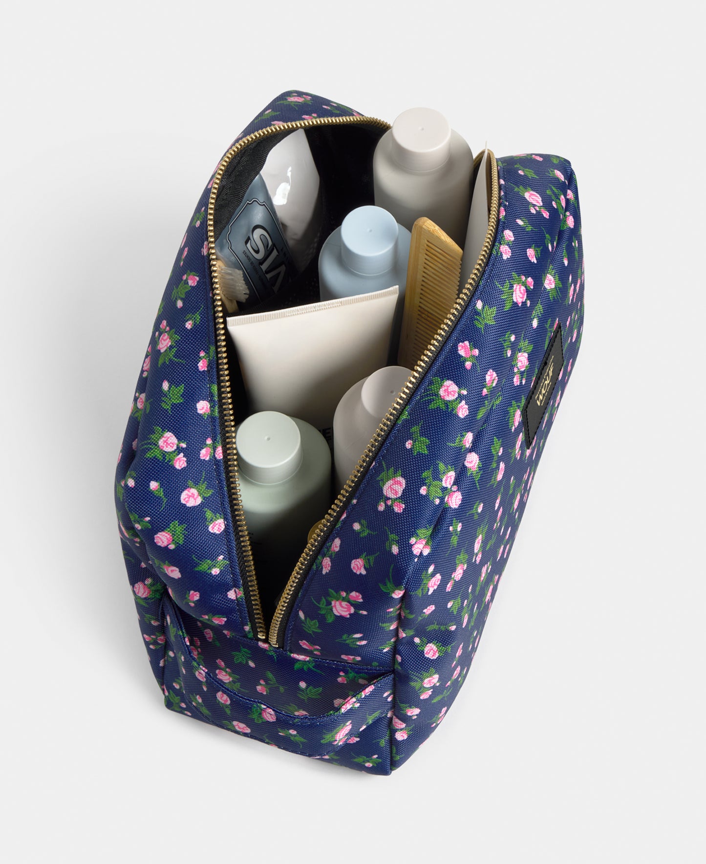 Interior detail of the Edith large toiletry bag with pink and green floral print on a navy background - Wouf