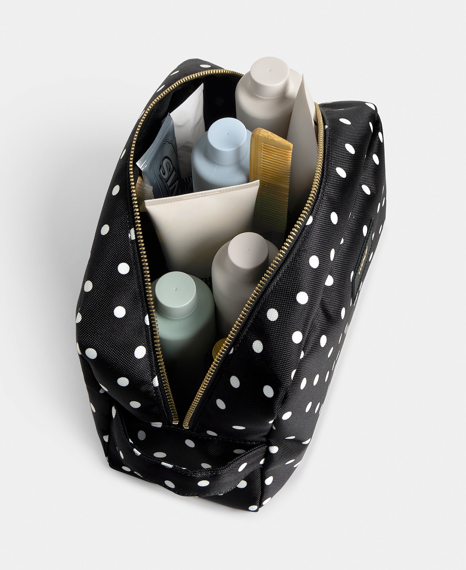 Interior detail of the Grace large toiletry bag with white polka dot print on a black background - Wouf