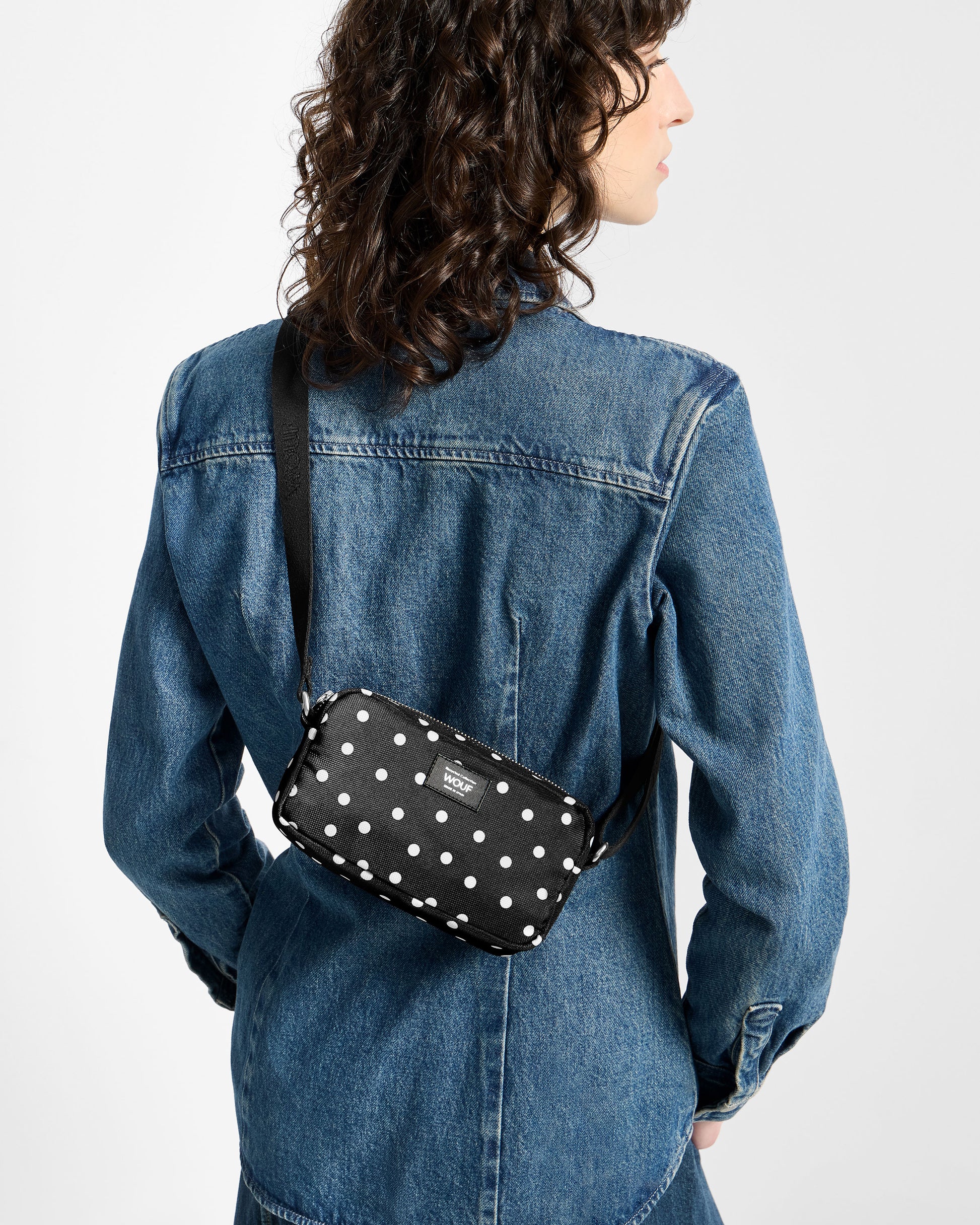 Model with mini bag with white polka dot print on a black background - Wouf