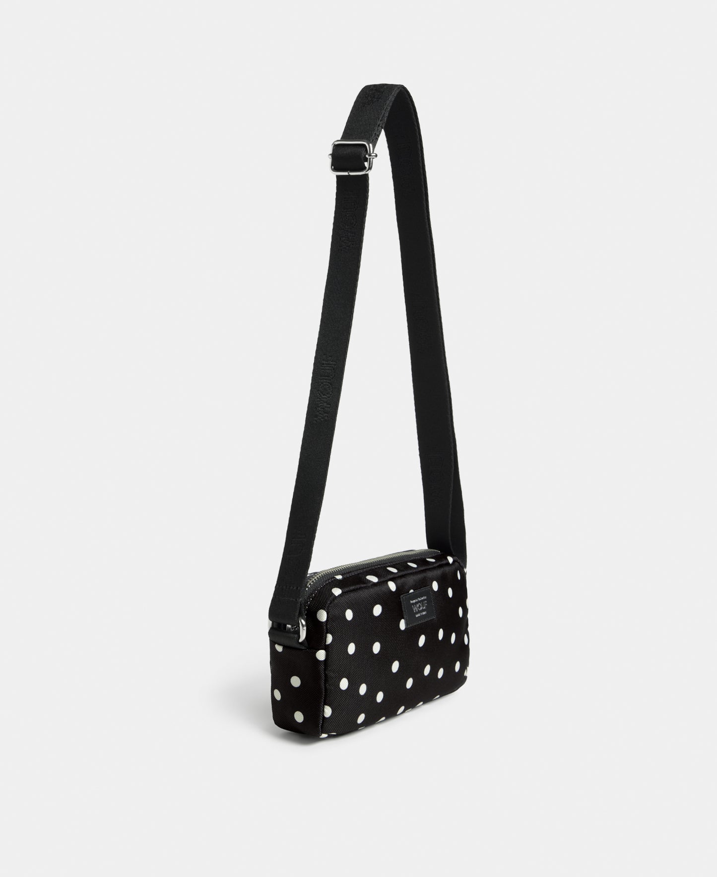 Side view of the Grace mini crossbody bag with white polka dot print on a black background - Wouf