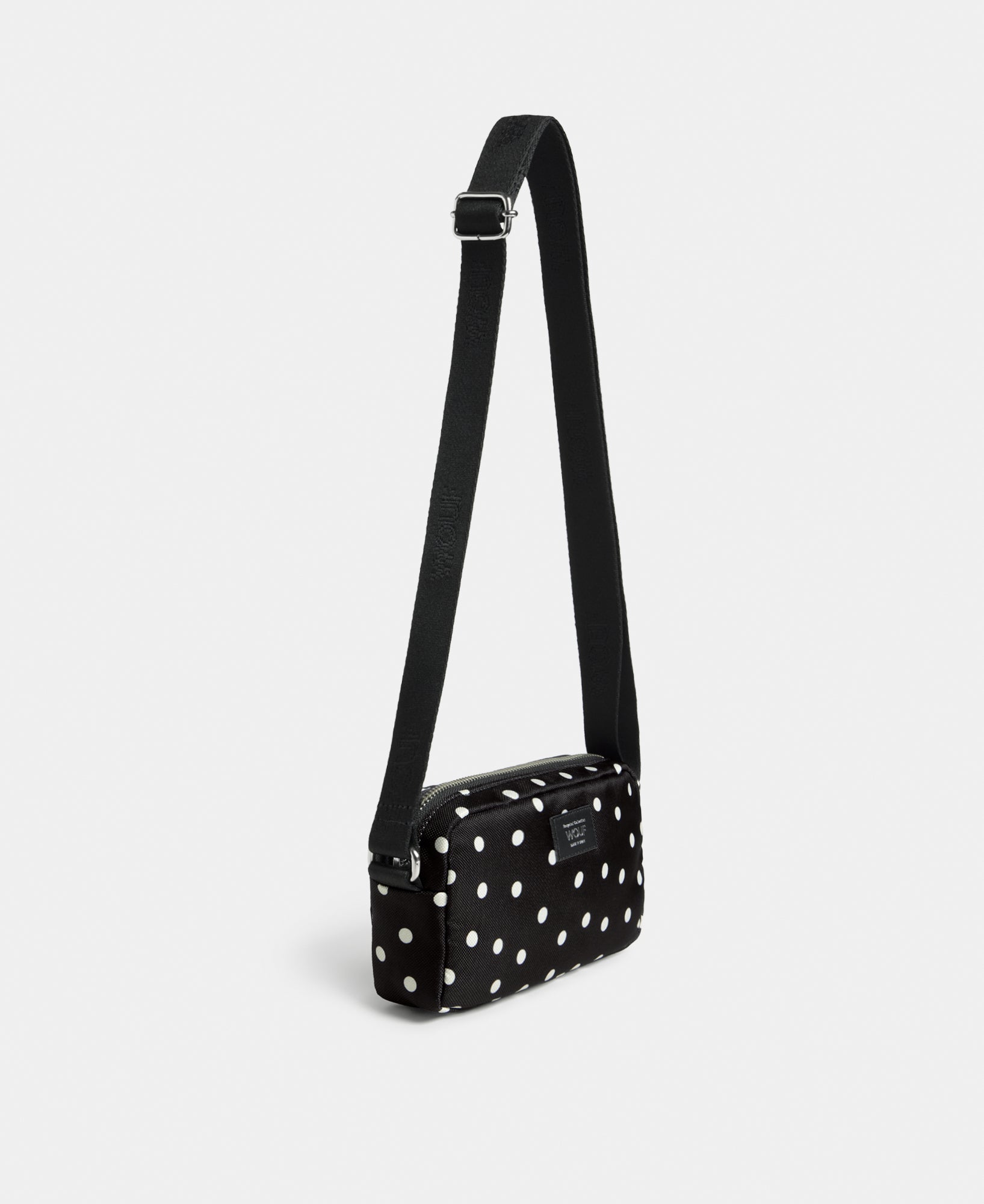 Side view of the Grace mini crossbody bag with white polka dot print on a black background - Wouf