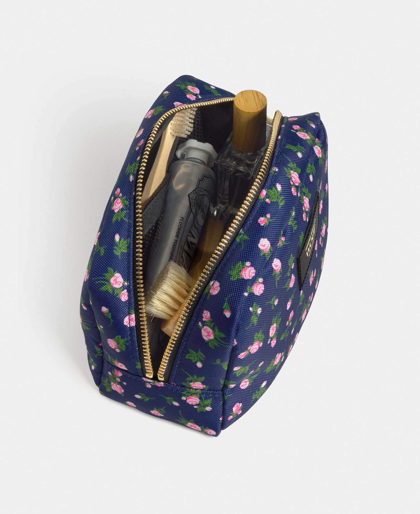 Interior detail of the Edith toiletry bag with pink and green floral print on a navy background - Wouf