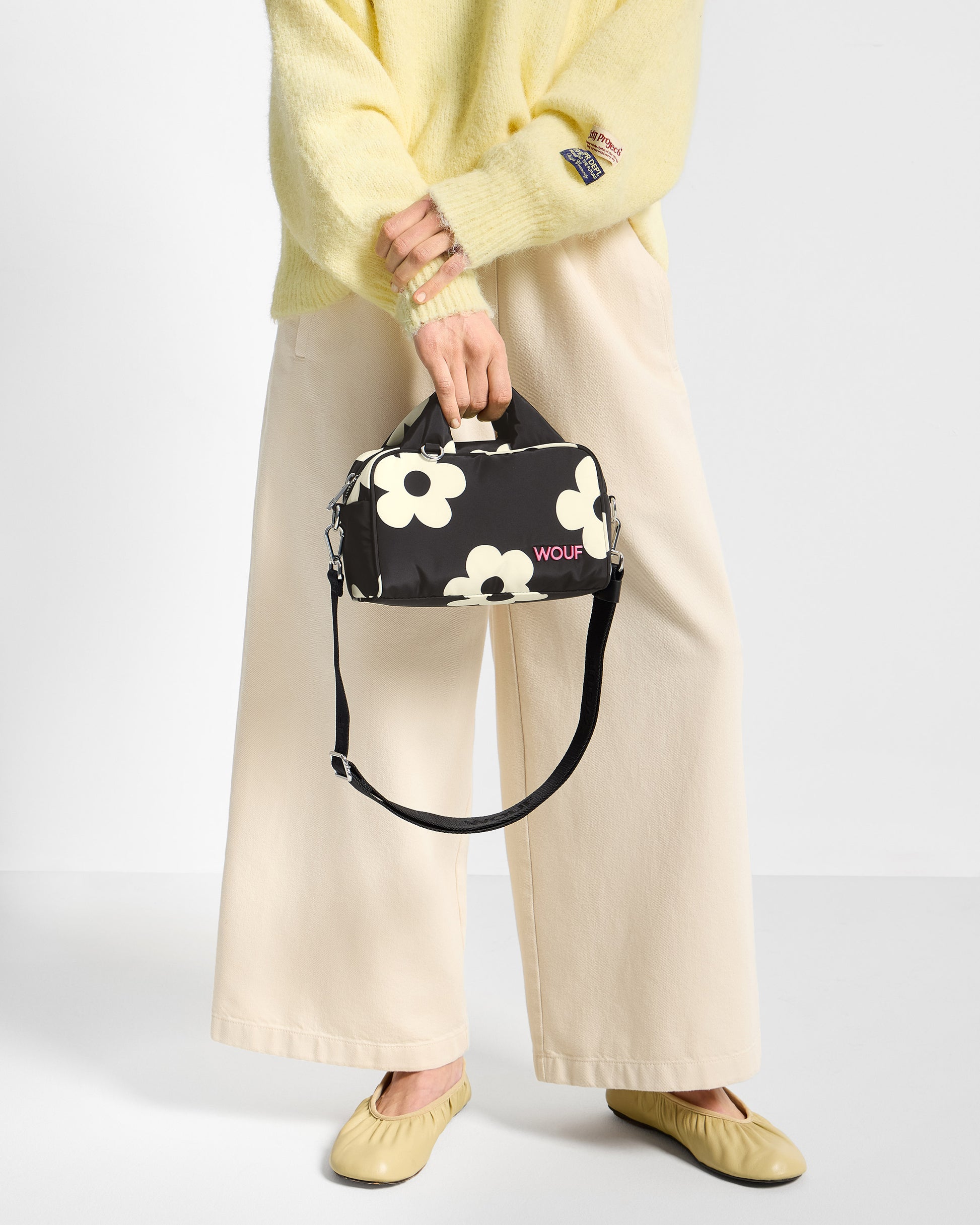 Detail of model with bowling bag with white floral print on a black background - Wouf