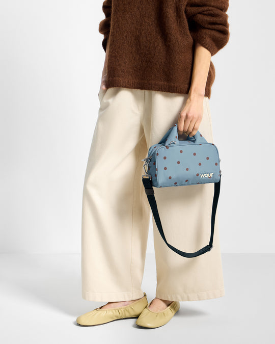 Détail de mannequin avec sac bowling à pois marrons sur fond bleu clair - Wouf
