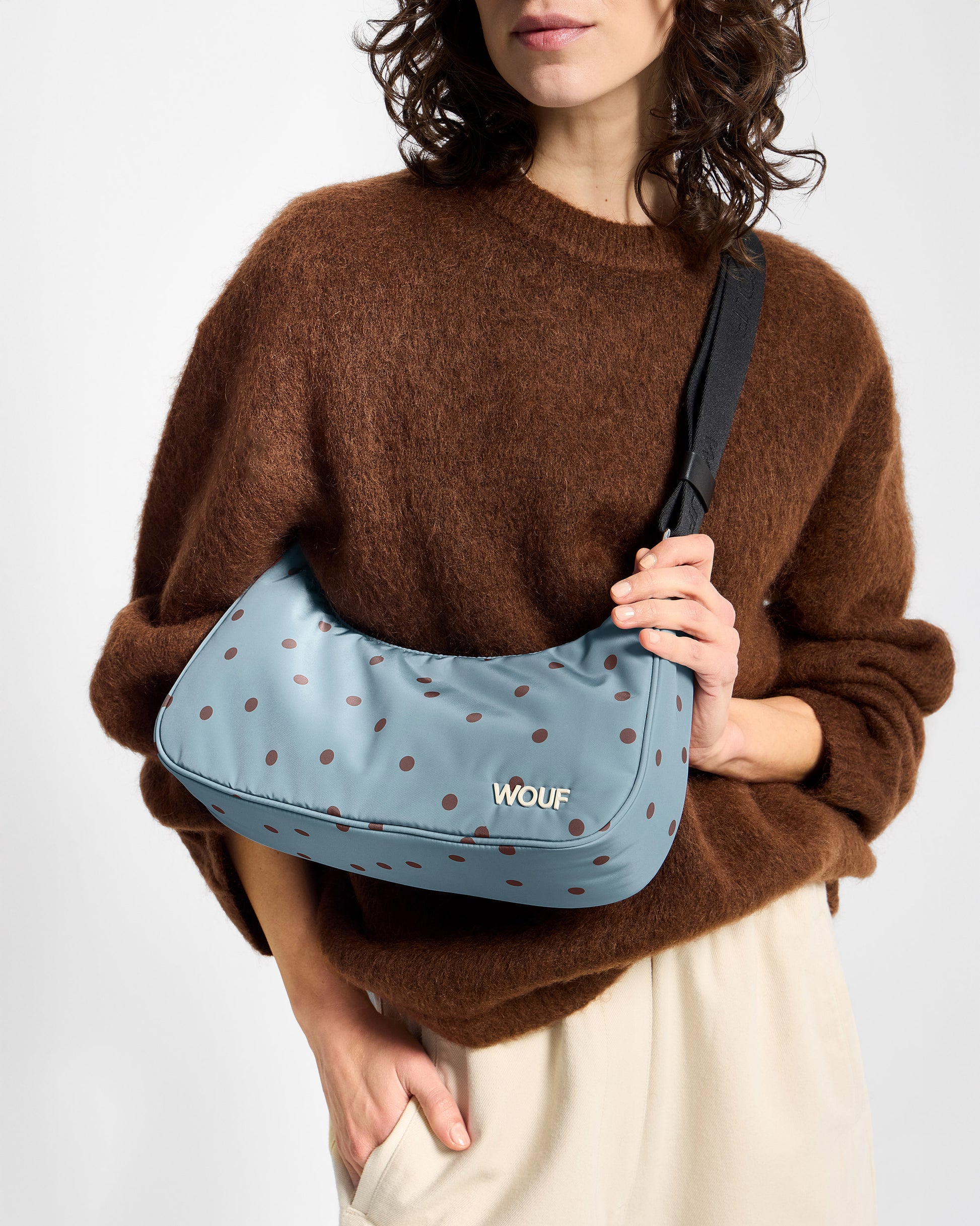 Détail de mannequin avec sac bandoulière à pois marrons sur fond bleu clair - Wouf
