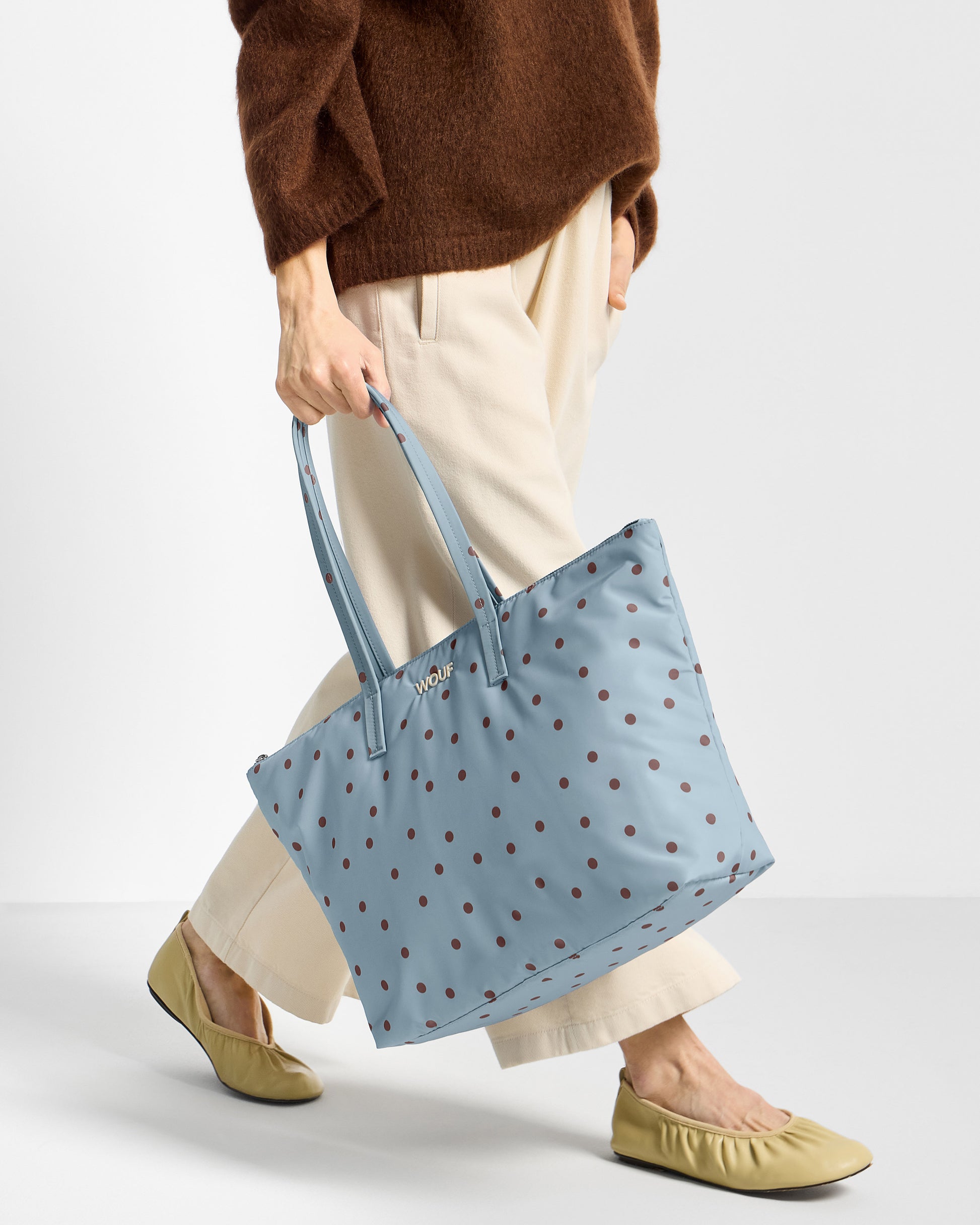 Détail de mannequin avec sac shopper à pois marrons sur fond bleu clair - Wouf