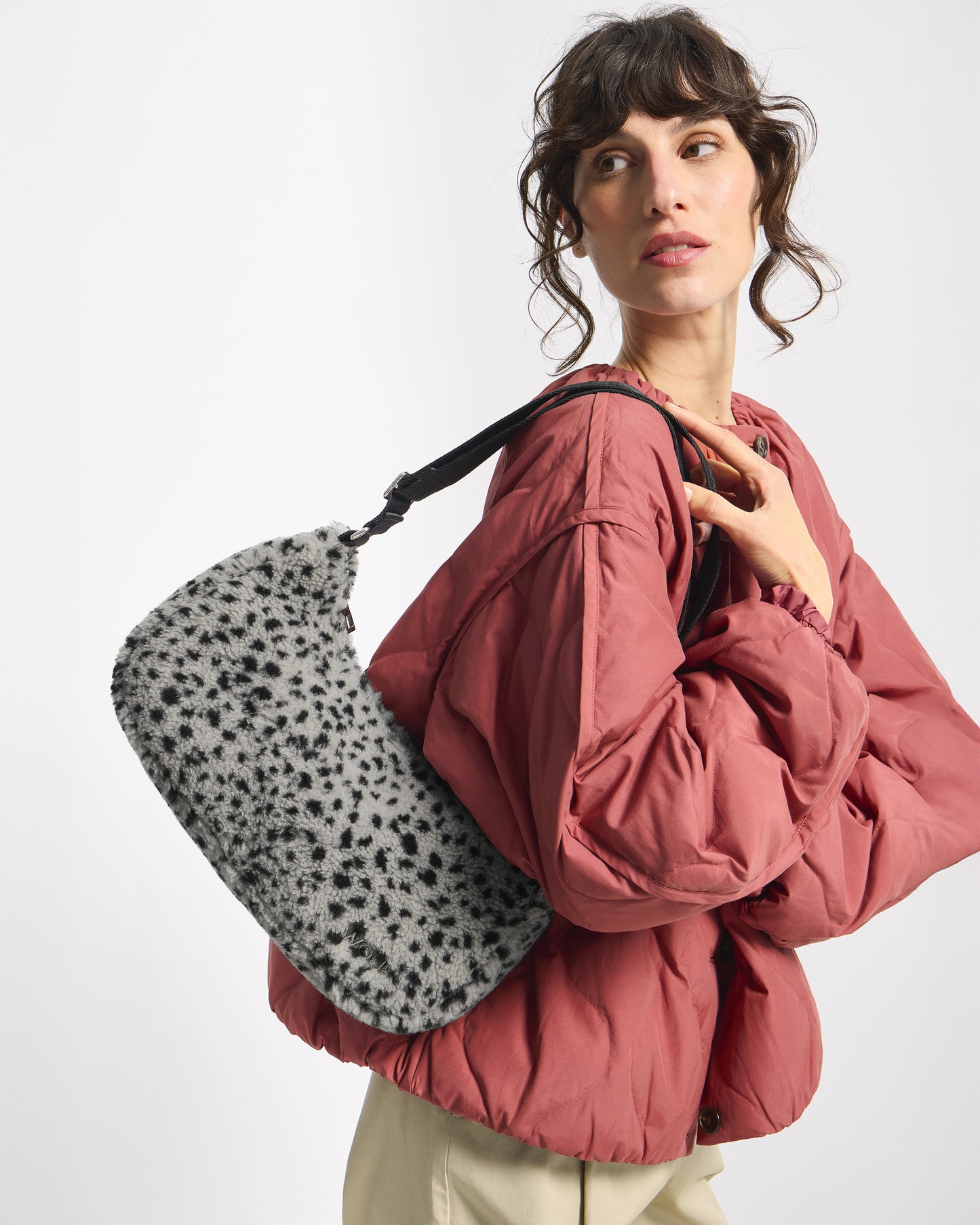 Detail of model with crossbody bag in teddy fabric with black micro print on a grey background - Wouf
