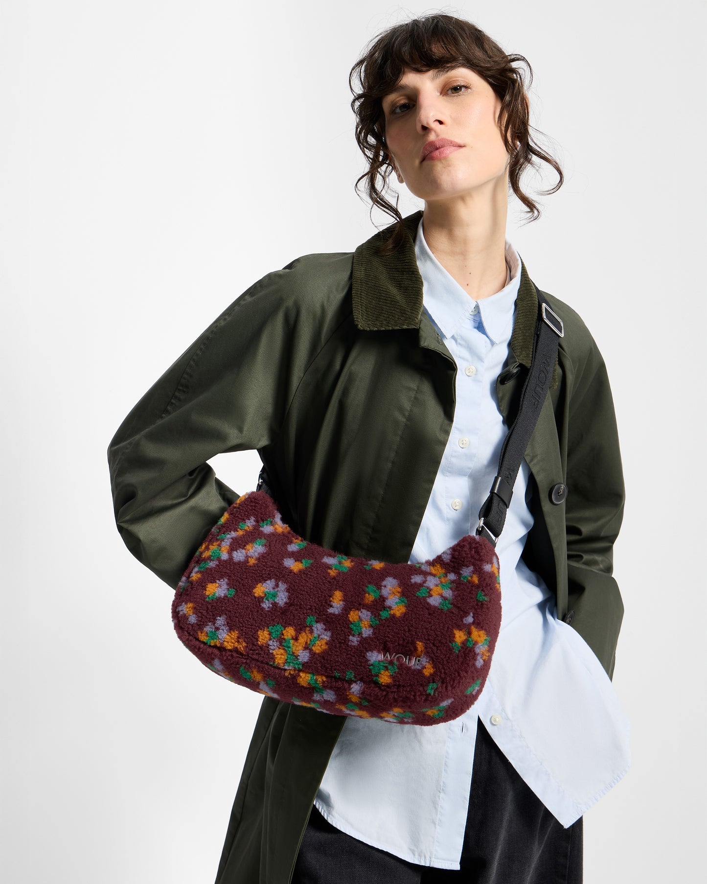 Detail of model with crossbody bag in teddy fabric with multicolour floral print on a burgundy background - Wouf