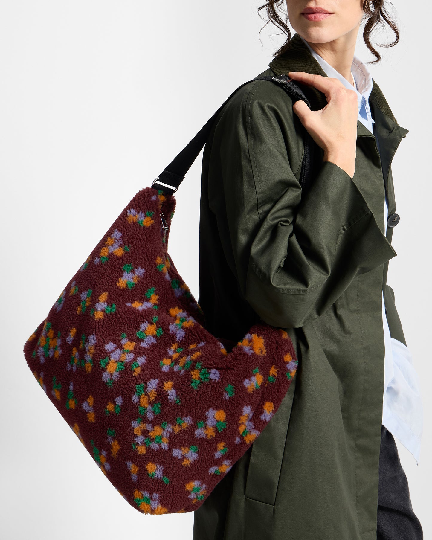 Detalle de modelo con bolso hobo de tejido teddy con estampado floral multicolor sobre fondo burdeos - Wouf