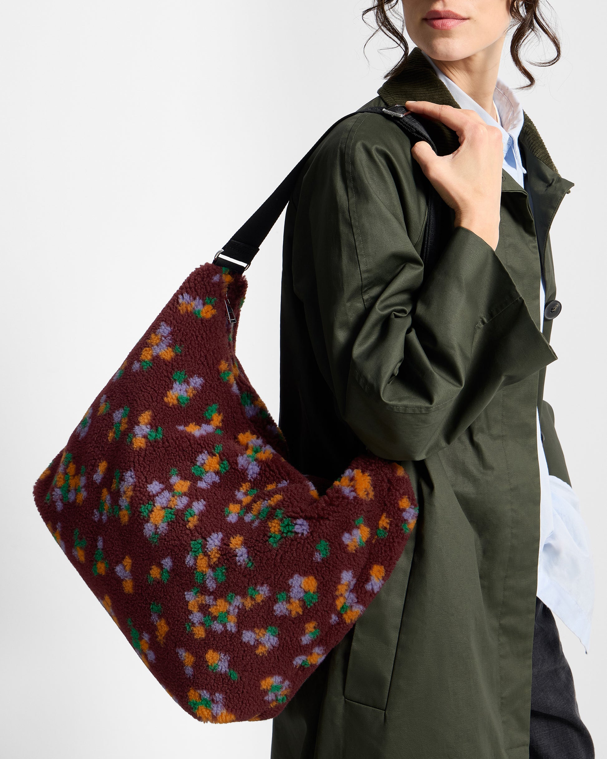 Detalle de modelo con bolso hobo de tejido teddy con estampado floral multicolor sobre fondo burdeos - Wouf
