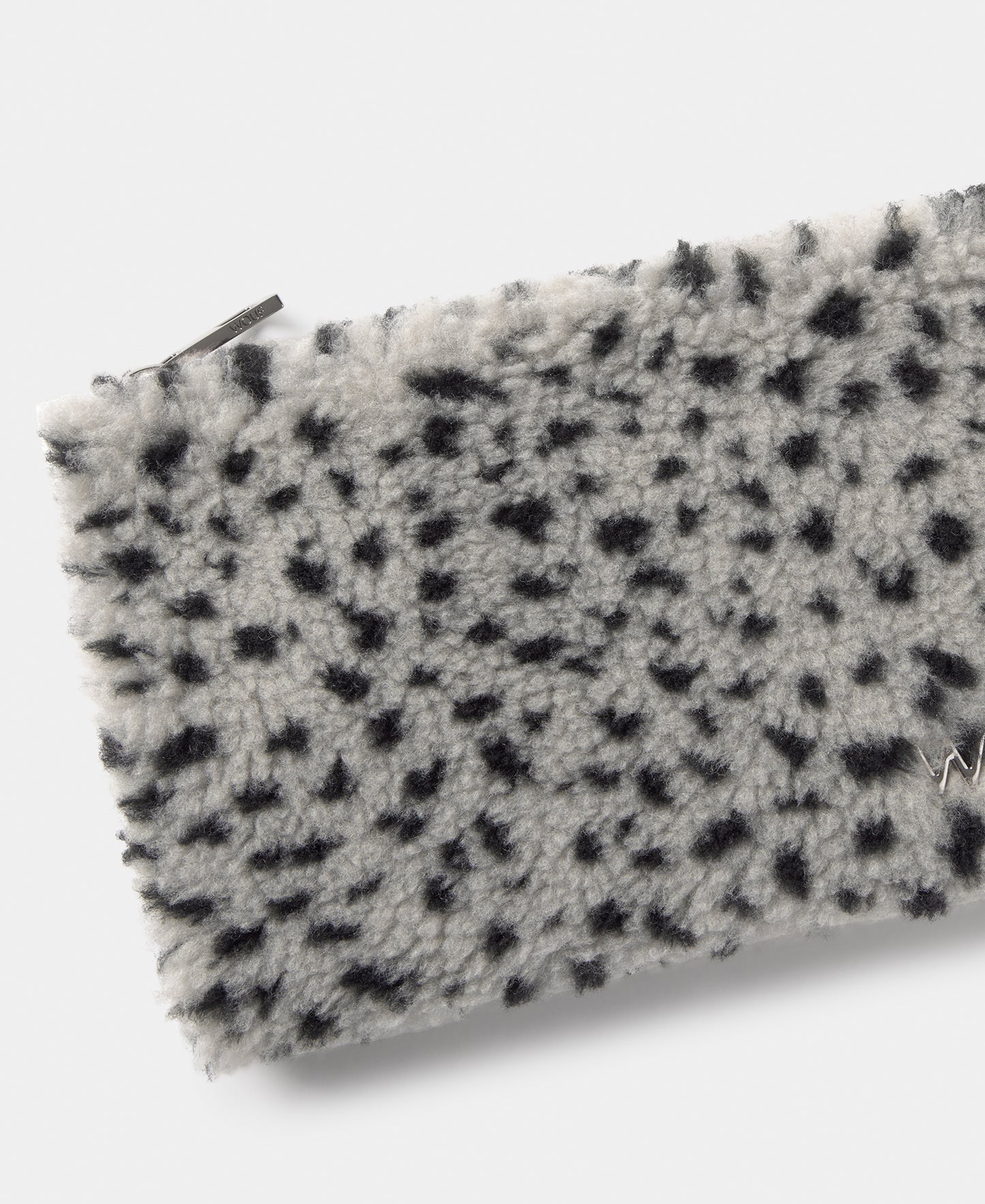 Detalle del pouch de tejido teddy con micro estampado negro sobre fondo gris - Wouf