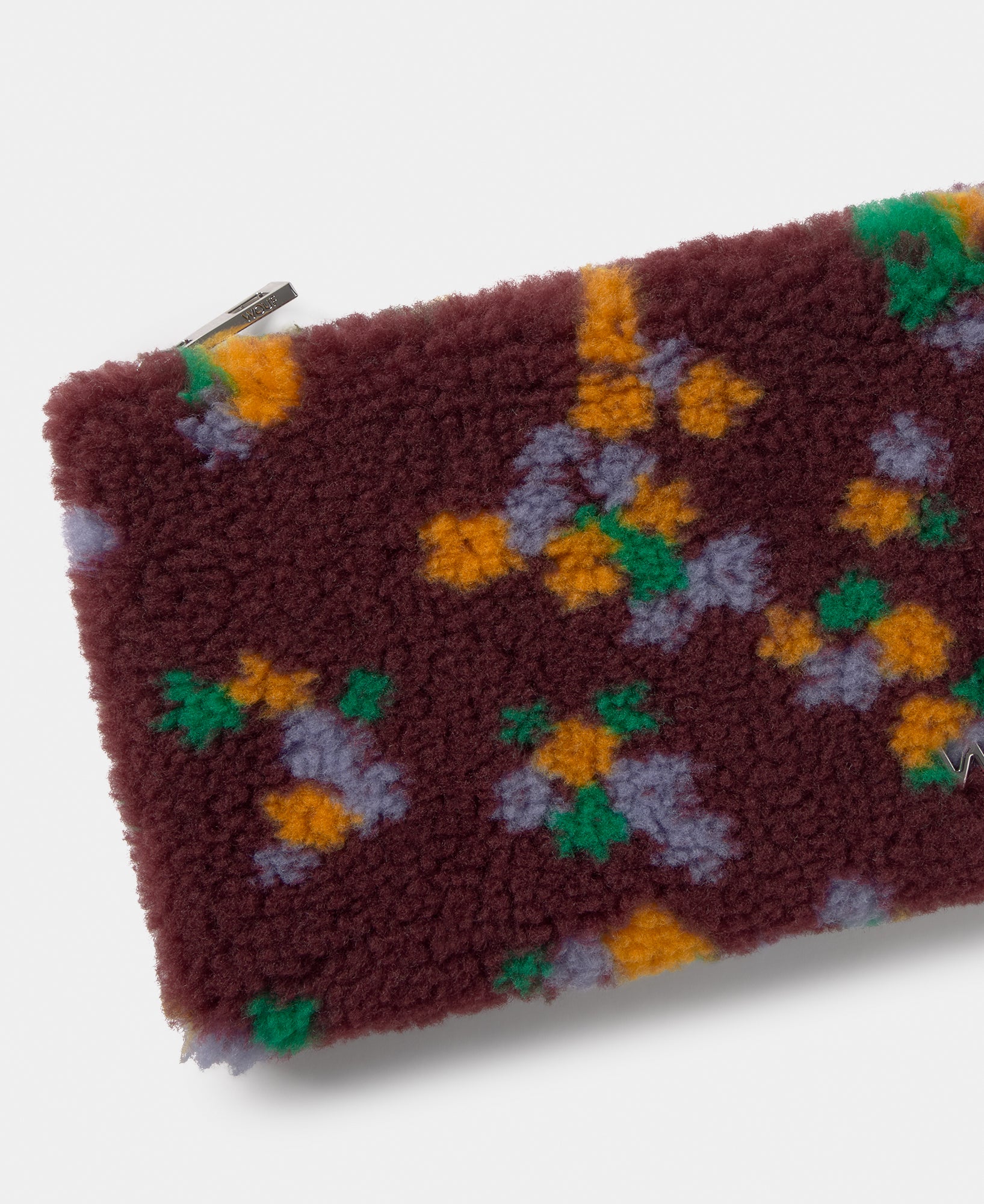 Detalle del pouch de tejido teddy con estampado floral multicolor sobre fondo burdeos - Wouf