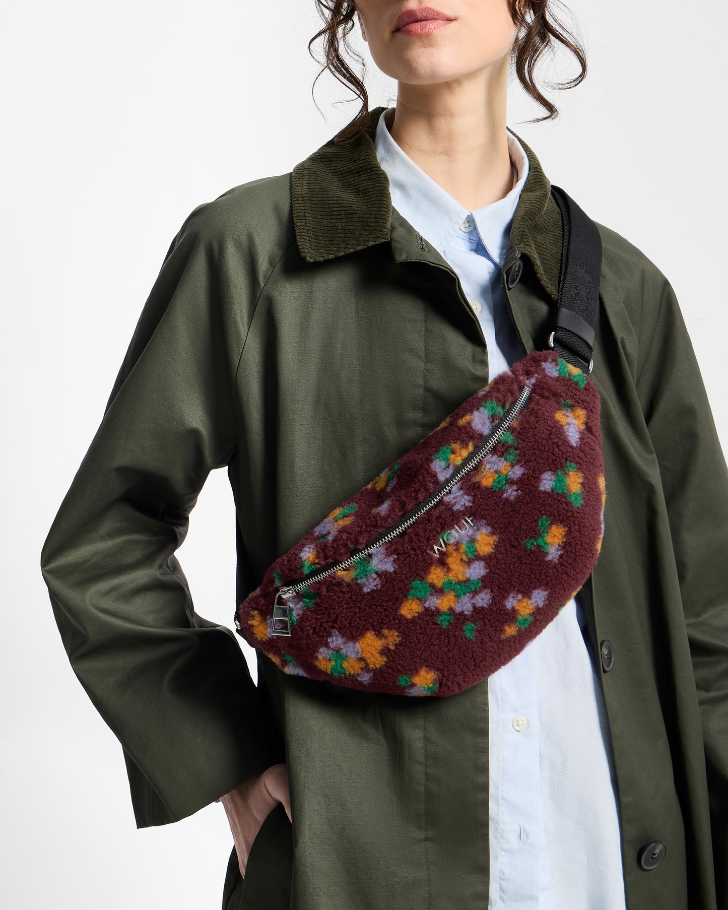Detail of model with waistbag in teddy fabric with multicolour floral print on a burgundy background - Wouf