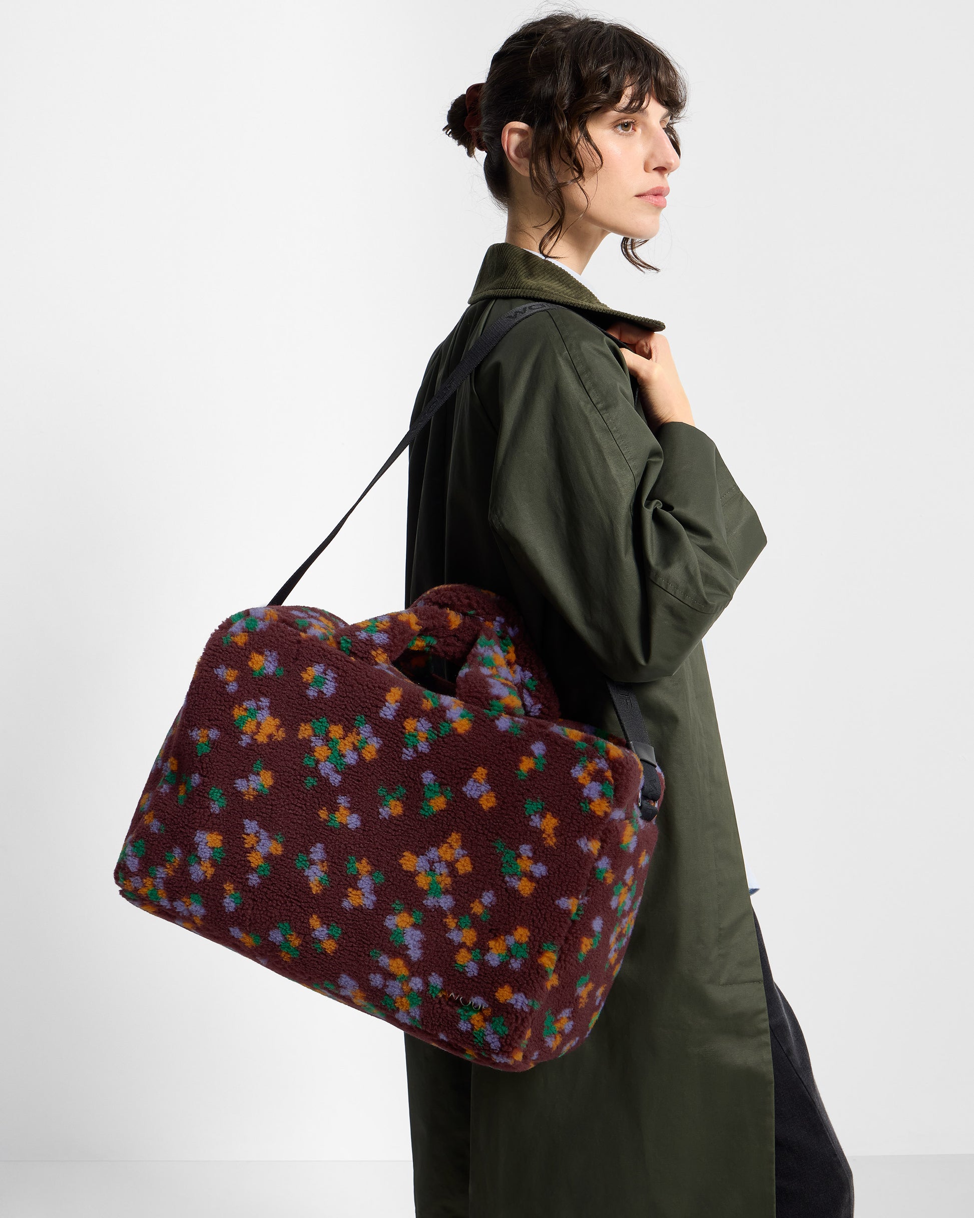 Detail of model with weekend bag in teddy fabric with multicolour floral print on a burgundy background - Wouf