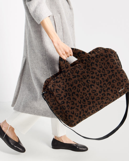 Détail de mannequin avec sac week-end en tissu teddy à imprimé léopard dans des tons marron et noir - Wouf